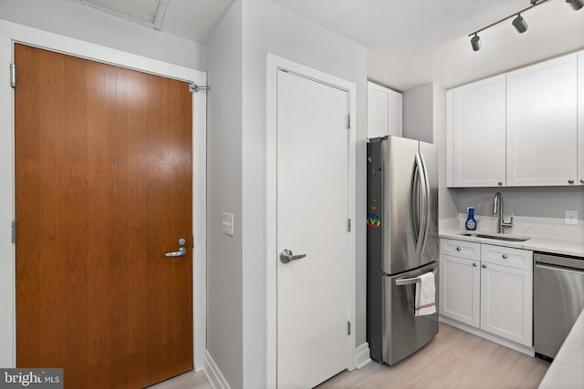 kitchen with white cabinetry, sink, stainless steel appliances, and light hardwood / wood-style floors