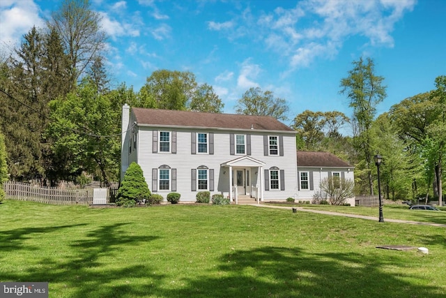 colonial inspired home with cooling unit and a front lawn