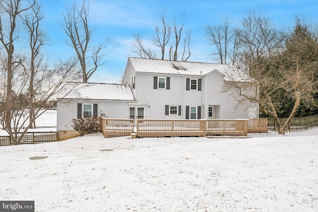 snow covered back of property with a wooden deck