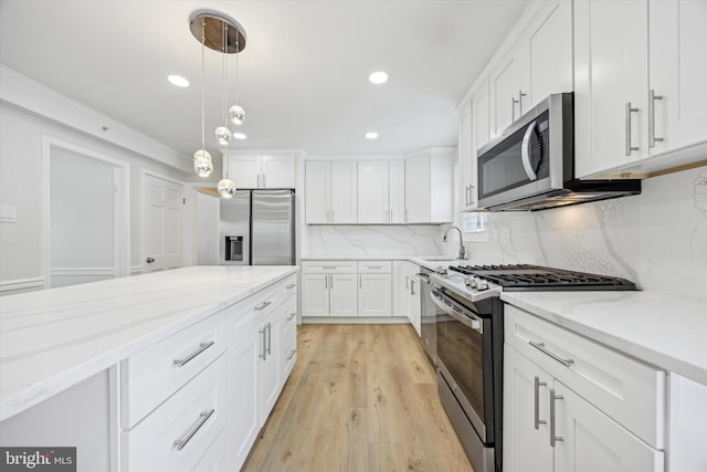 kitchen featuring pendant lighting, sink, light stone countertops, white cabinetry, and stainless steel appliances