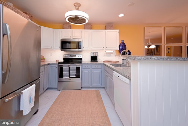 kitchen with sink, backsplash, kitchen peninsula, white cabinets, and appliances with stainless steel finishes