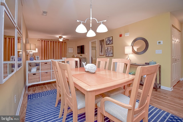 dining space featuring hardwood / wood-style flooring and ceiling fan with notable chandelier