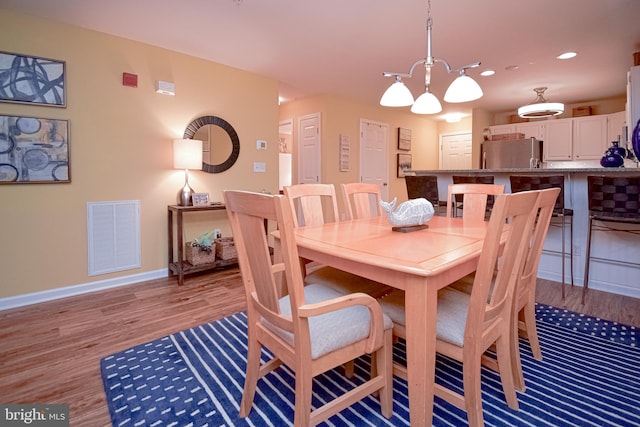 dining room with light wood-type flooring and a chandelier