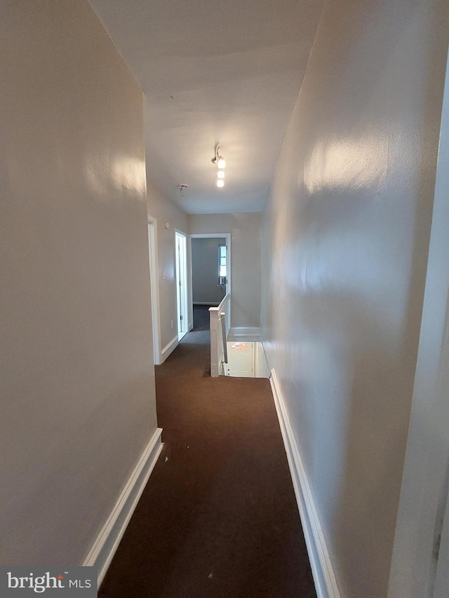 hallway featuring dark colored carpet