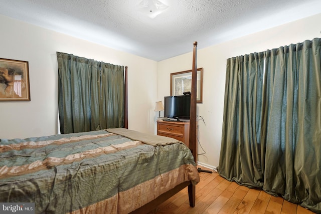 bedroom featuring a textured ceiling and light hardwood / wood-style flooring