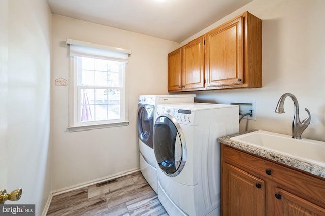 laundry room with sink, washer and clothes dryer, and cabinets