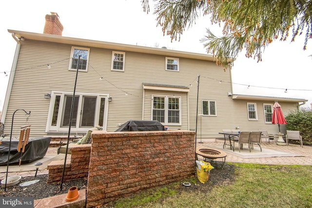 rear view of house with a fire pit and a patio area