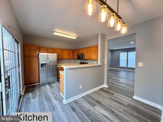 kitchen featuring pendant lighting, plenty of natural light, stainless steel appliances, and light hardwood / wood-style flooring