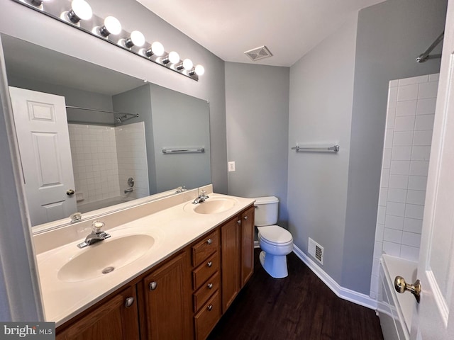 full bathroom with washtub / shower combination, hardwood / wood-style floors, vanity, and toilet