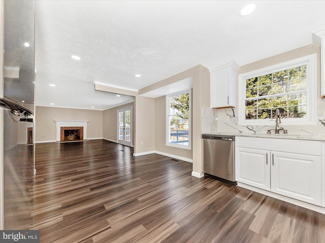 kitchen with dishwasher, light stone countertops, white cabinetry, and sink