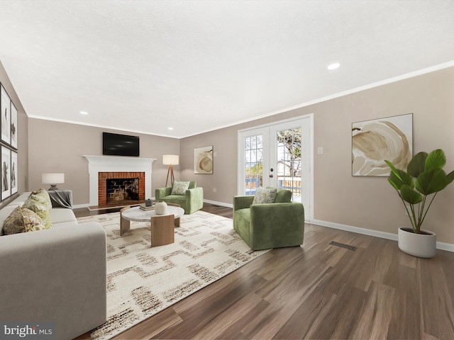 living room with a fireplace, crown molding, french doors, and hardwood / wood-style flooring