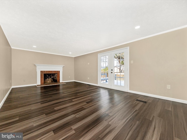 unfurnished living room featuring dark hardwood / wood-style flooring, ornamental molding, a fireplace, and french doors