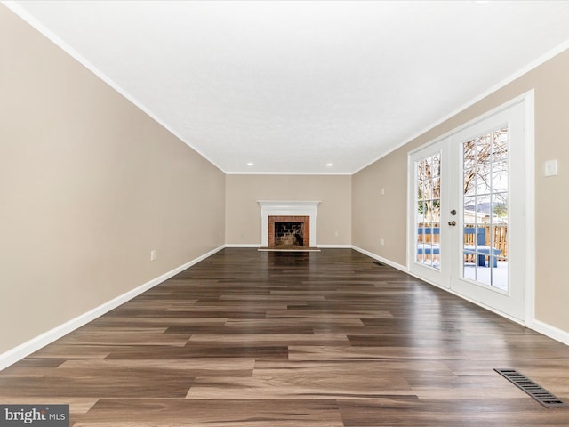 unfurnished living room featuring french doors, dark hardwood / wood-style flooring, a brick fireplace, and crown molding