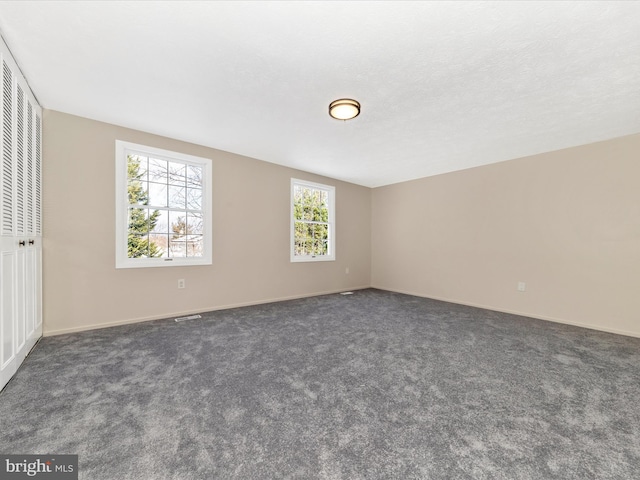 spare room with dark carpet