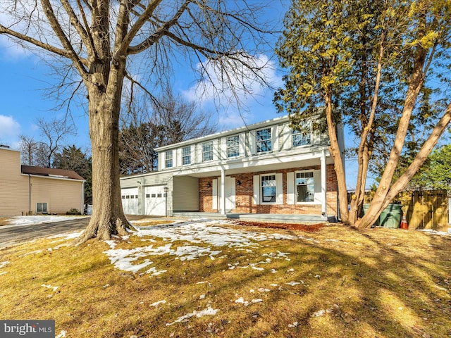 front facade with covered porch, a garage, and a front yard