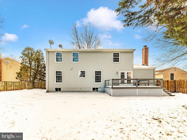 snow covered rear of property with a deck