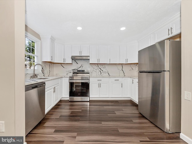 kitchen featuring appliances with stainless steel finishes, backsplash, dark wood-type flooring, sink, and white cabinets