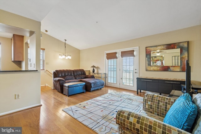 living room with ceiling fan with notable chandelier, lofted ceiling, and hardwood / wood-style flooring