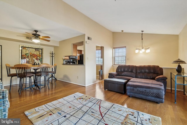 living room with vaulted ceiling, hardwood / wood-style floors, and ceiling fan with notable chandelier