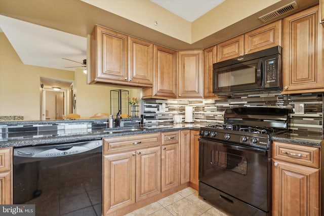 kitchen featuring black appliances, dark stone countertops, light tile patterned floors, and sink