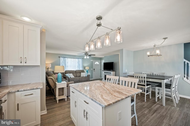 kitchen featuring decorative light fixtures, decorative backsplash, ceiling fan with notable chandelier, and white cabinetry