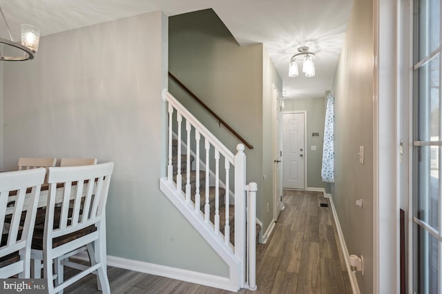 foyer with dark wood-type flooring and an inviting chandelier