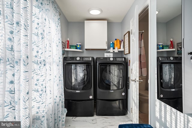 clothes washing area featuring cabinets and washer and clothes dryer