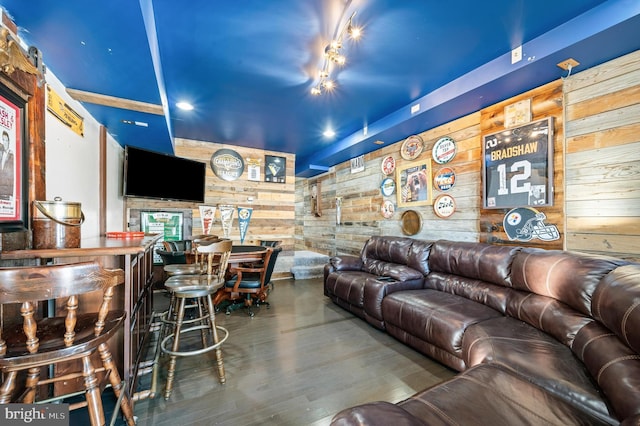 living room with wood-type flooring, bar area, and wood walls