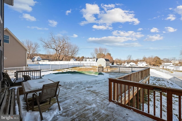 snow covered deck with a storage shed and a covered pool