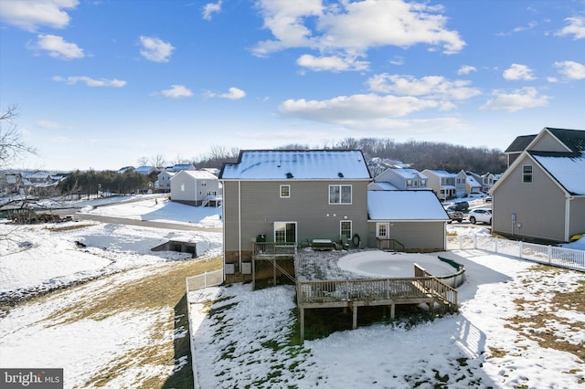 snow covered rear of property with a wooden deck