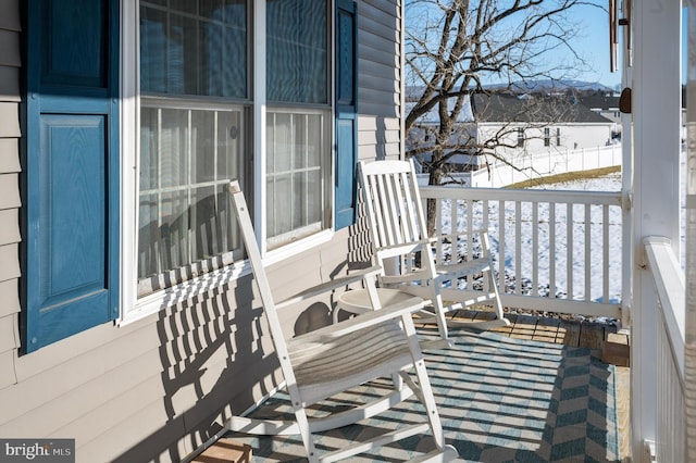 snow covered back of property with a porch