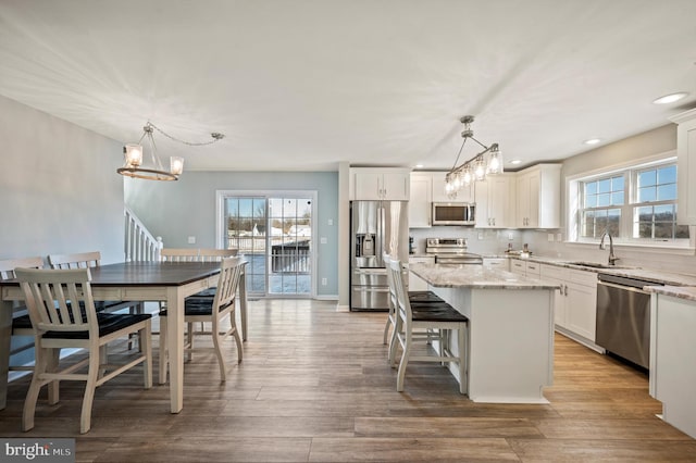 kitchen featuring decorative light fixtures, light stone counters, appliances with stainless steel finishes, and a center island