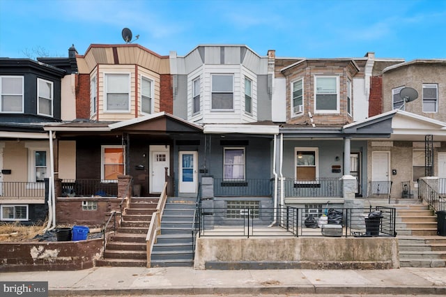 townhome / multi-family property featuring covered porch and stairs