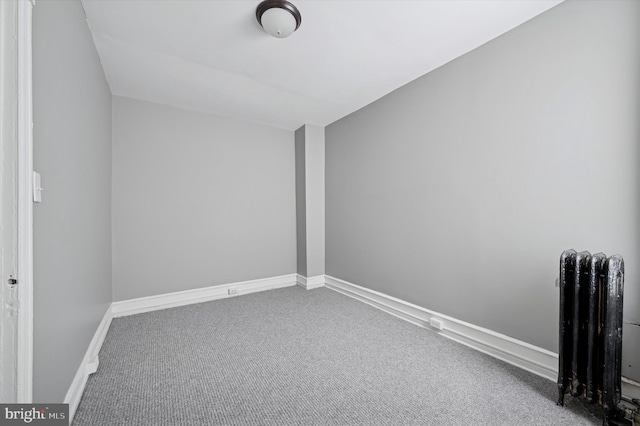 carpeted empty room with radiator and baseboards