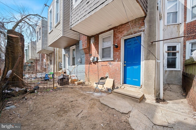 property entrance featuring brick siding and fence