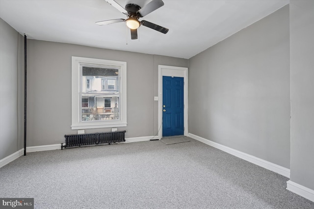 spare room with radiator heating unit, carpet, a ceiling fan, and baseboards