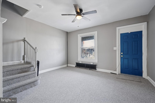 carpeted entryway featuring a ceiling fan, radiator, stairway, and baseboards