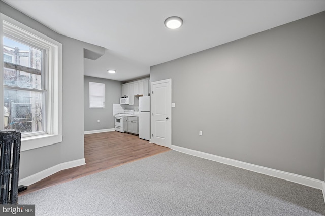 interior space with carpet, baseboards, and wood finished floors