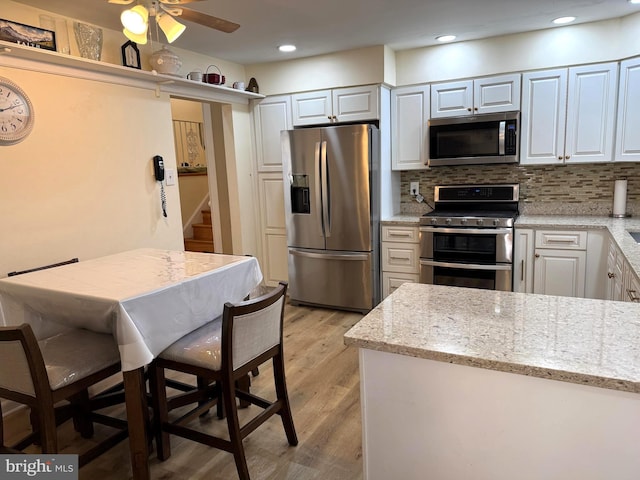 kitchen featuring light stone counters, light wood-type flooring, tasteful backsplash, and stainless steel appliances