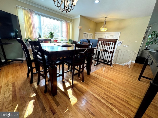 dining space featuring light wood finished floors, a chandelier, crown molding, and baseboards