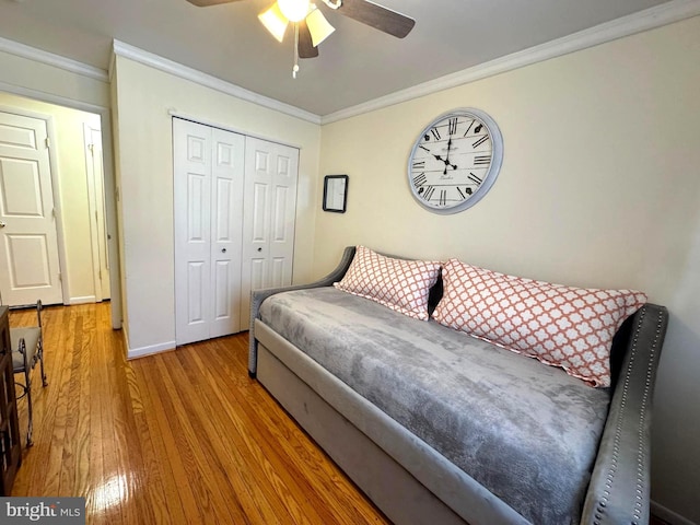 bedroom with crown molding, ceiling fan, baseboards, wood finished floors, and a closet