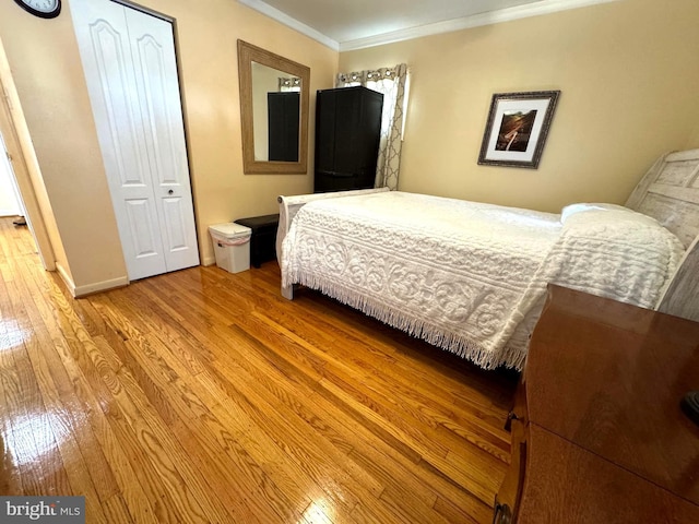 bedroom featuring a closet, crown molding, light wood-type flooring, and baseboards