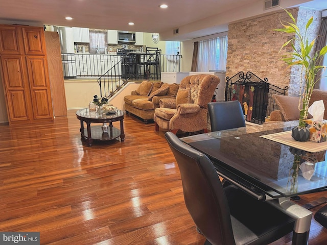 dining space with visible vents, stairs, recessed lighting, a fireplace, and wood finished floors