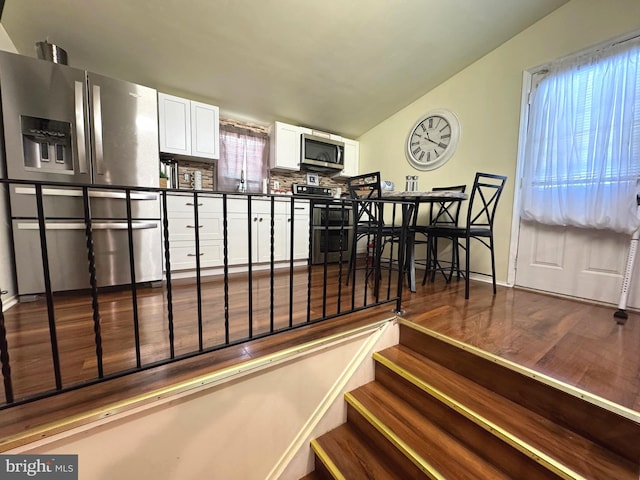 stairway featuring wood finished floors and vaulted ceiling