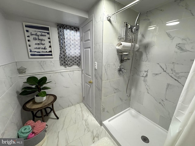 bathroom with tile walls, marble finish floor, and a stall shower