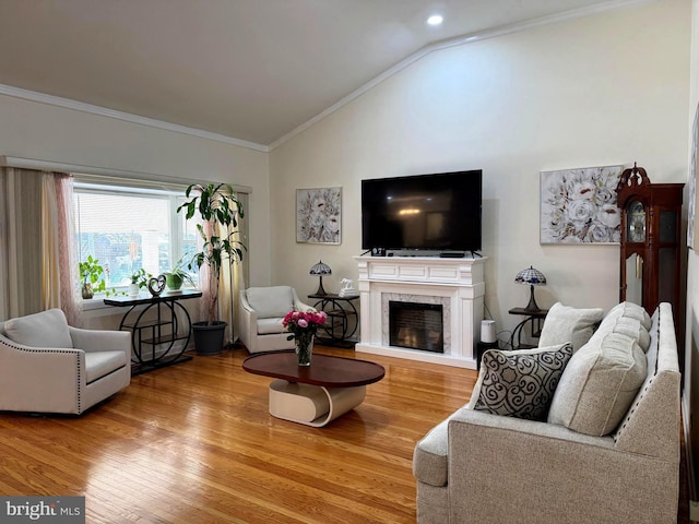 living area featuring vaulted ceiling, crown molding, wood finished floors, and a high end fireplace