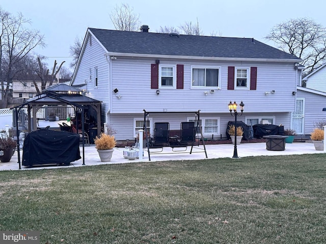 back of property featuring a gazebo, a lawn, a shingled roof, and a patio