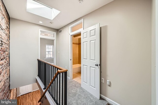 hall featuring light carpet and a skylight