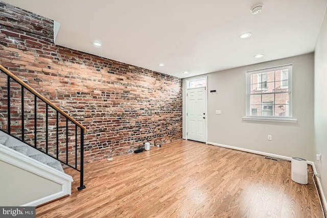 foyer entrance with light hardwood / wood-style flooring and brick wall