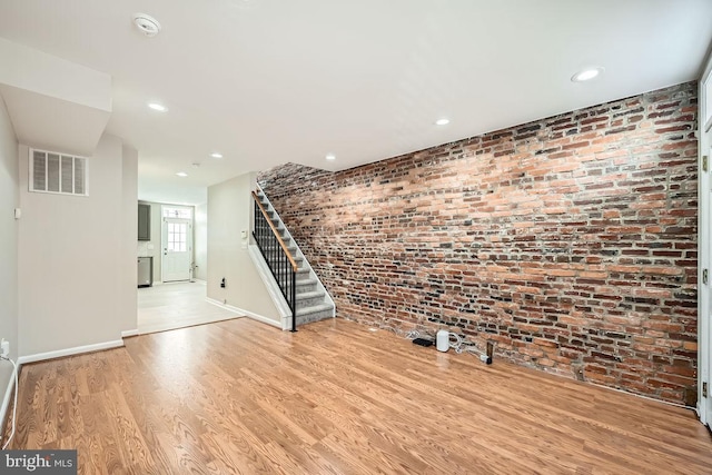 unfurnished living room featuring light hardwood / wood-style floors and brick wall